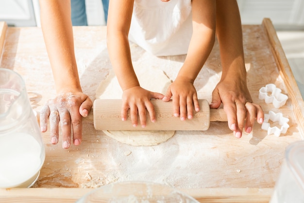 Manos con rodillo de cocina en masa