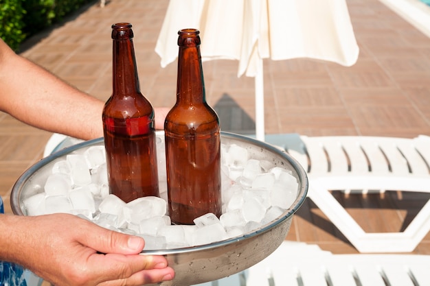 Foto gratuita manos sosteniendo una bandeja llena de cubitos de hielo y cerveza