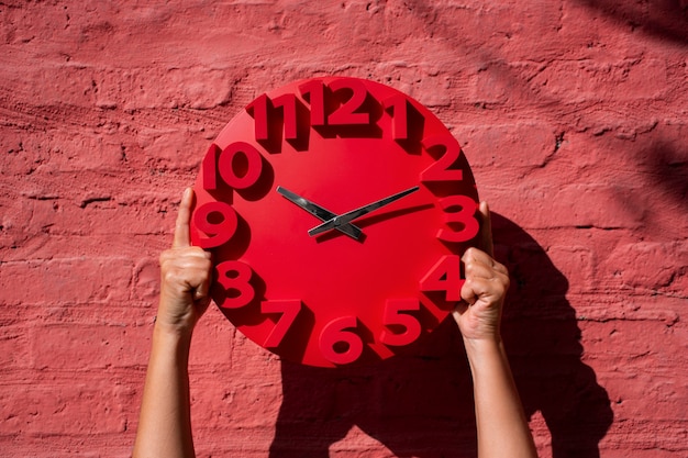 Manos sosteniendo bodegón de reloj de pared