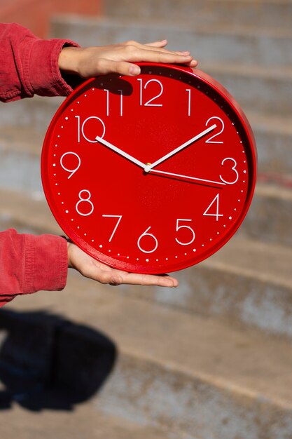 Manos sosteniendo bodegón de reloj de pared