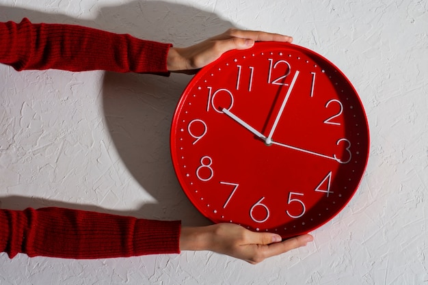 Manos sosteniendo bodegón de reloj de pared