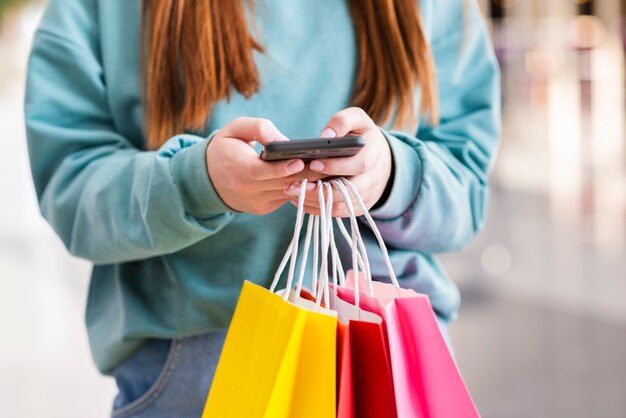 Manos sosteniendo bolsas de papel y teléfono