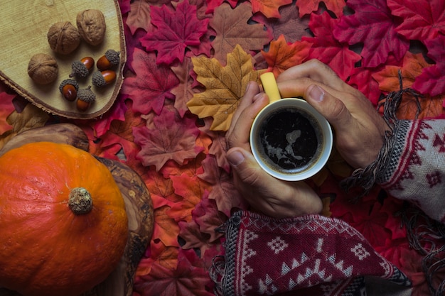 Manos sosteniendo el café en la composición de la hoja de otoño