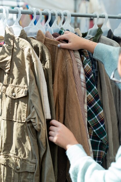 Manos sosteniendo la chaqueta en el mercado de segunda mano