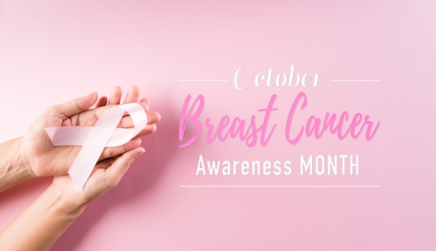 Manos sosteniendo cintas de color rosa concienciación sobre el cáncer de mama color del arco simbólico sensibilización