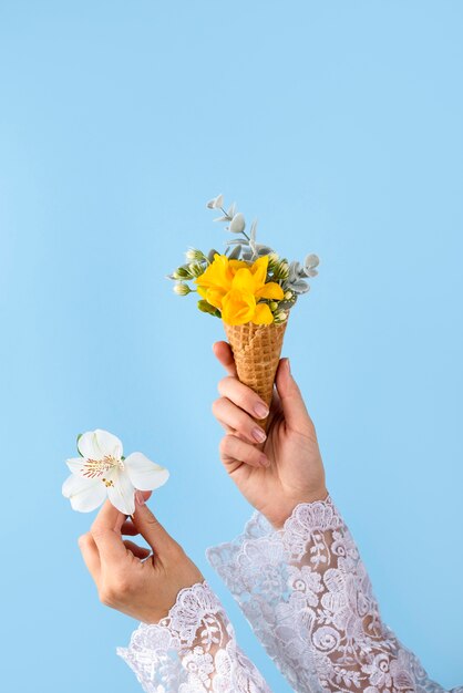 Manos sosteniendo cono de helado y flor