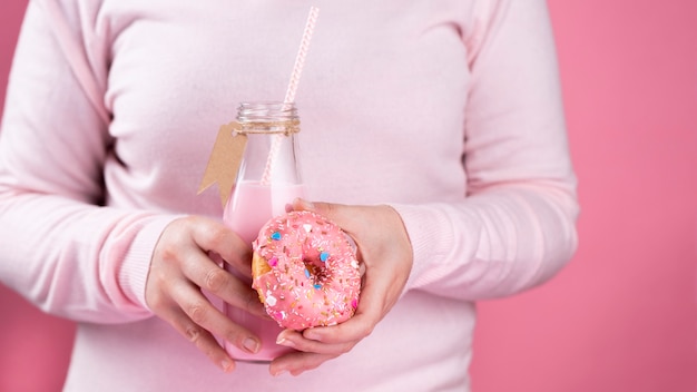 Foto gratuita manos sosteniendo donut rosa