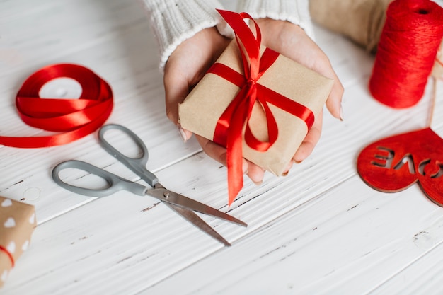 Manos sosteniendo envuelto regalo para San Valentín