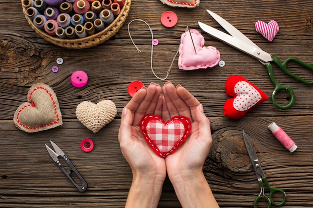 Manos sosteniendo una forma de corazón rojo sobre fondo de madera