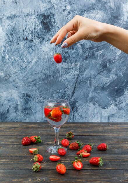 Manos sosteniendo fresas en tablero de madera