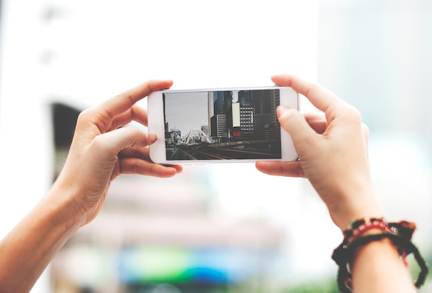 Manos sosteniendo la pantalla del teléfono móvil que muestra la vista de la ciudad del paisaje del metro photo