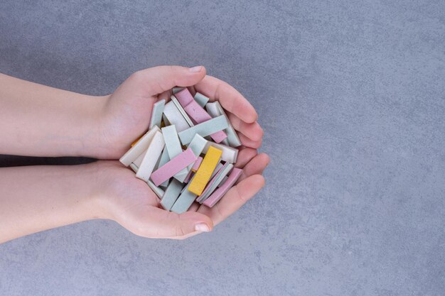 Manos sosteniendo un pequeño montón de palos de chicle en la superficie de mármol