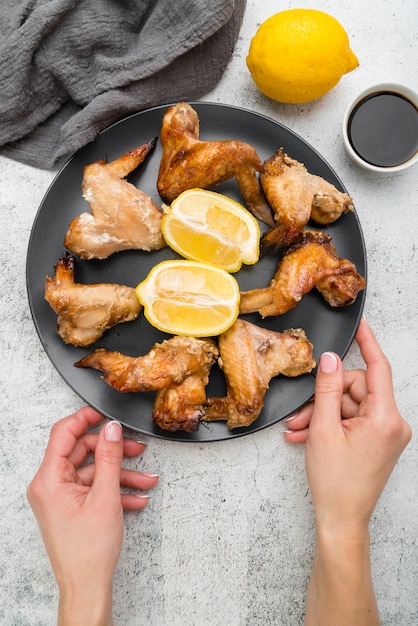 Foto gratuita manos sosteniendo un plato con deliciosas alitas de cocina