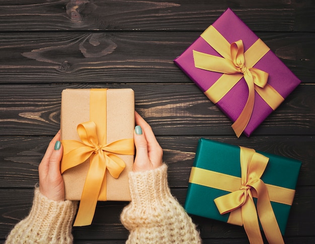 Manos sosteniendo presente para Navidad sobre fondo de madera