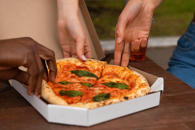 Manos sosteniendo rebanadas de pizza de alto ángulo