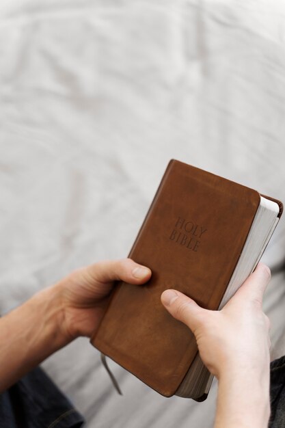 Manos sosteniendo la sagrada biblia alto ángulo