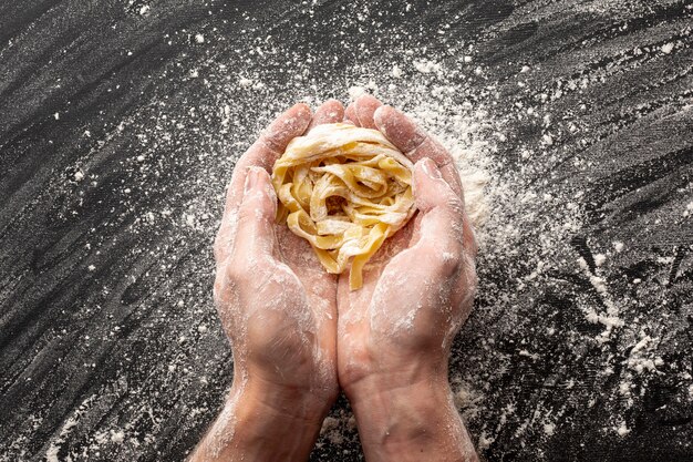 Manos sosteniendo tagliatelle crudo