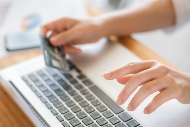 Manos sosteniendo una tarjeta de crédito y usando una computadora portátil para compras en línea