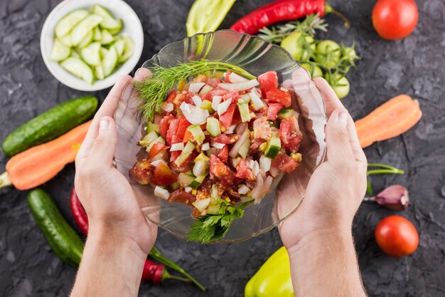 Manos sosteniendo tazón de ensalada con fondo borroso