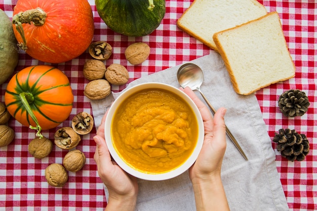 Manos sosteniendo el tazón de puré de calabaza