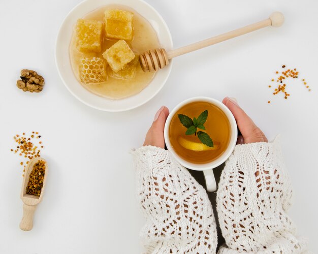 Manos sosteniendo té con miel