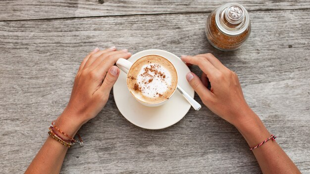 las manos sostienen una taza de café.