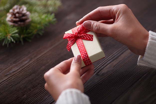 Manos sujetando una caja de regalo con una mesa de madera oscura