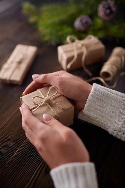 Manos sujetando cajas de regalos marrones con cordel