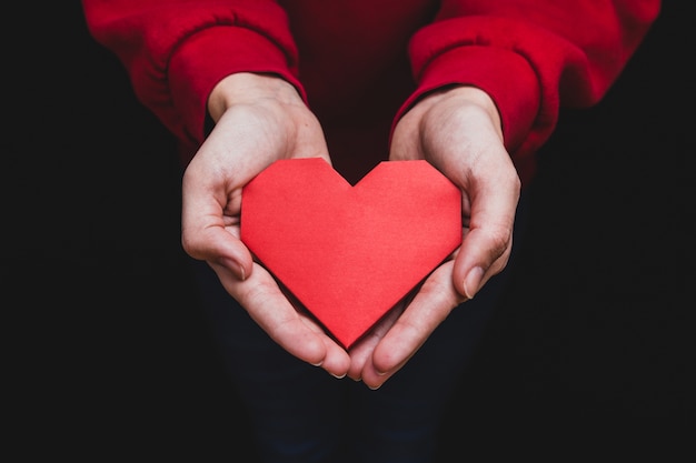 Manos sujetando un corazón en un fondo oscuro