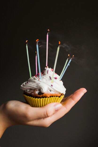 Manos sujetando muffin para cumpleaños