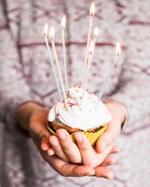 Manos sujetando muffin para cumpleaños