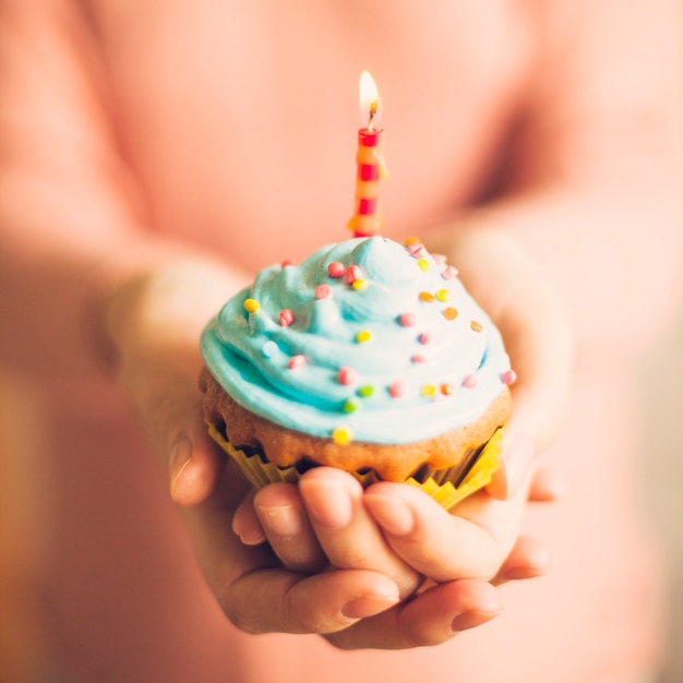 Foto gratuita manos sujetando muffin para cumpleaños