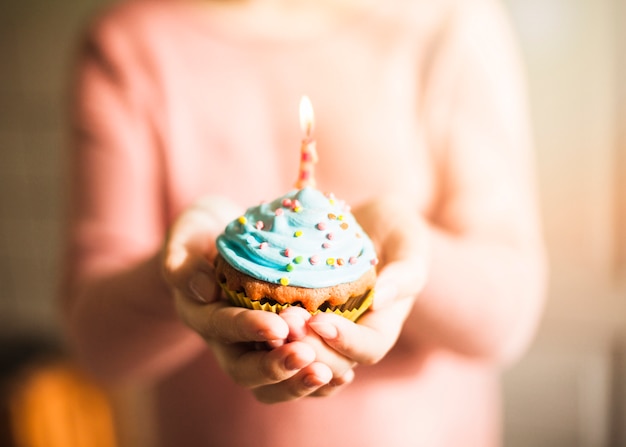 Foto gratuita manos sujetando muffin para cumpleaños