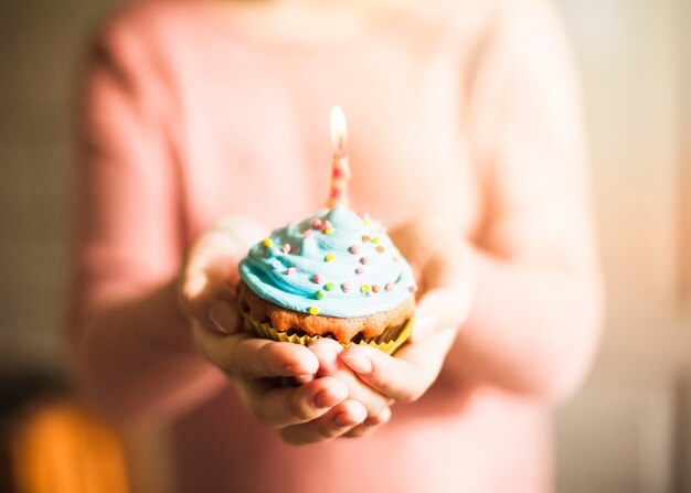 Manos sujetando muffin para cumpleaños