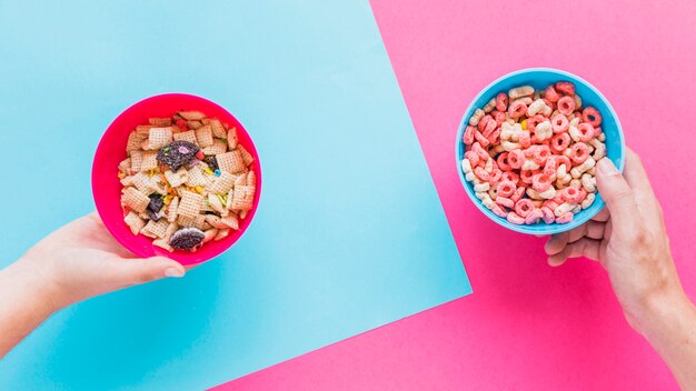 Manos sujetando tazones con cereales.