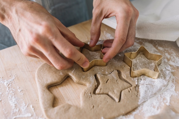 Manos usando cortador de galletas en pastelería