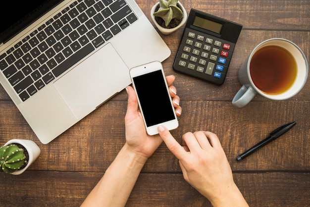 Manos usando teléfono inteligente en el espacio de trabajo