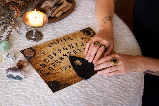 Manos usando un viejo tablero de ouija de madera de alto ángulo