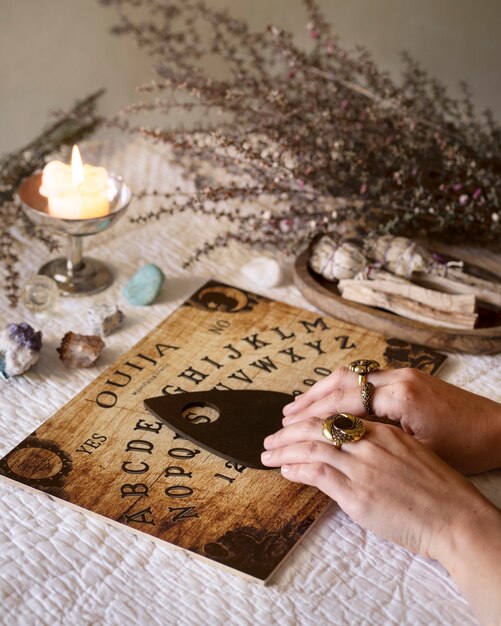 Manos usando un viejo tablero de ouija de madera