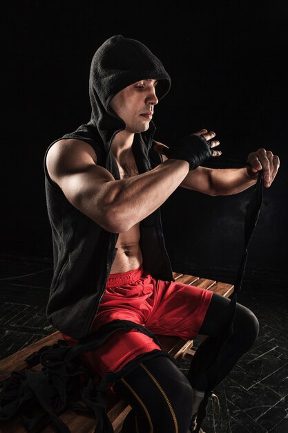 Las manos con vendaje de kickboxing de entrenamiento de hombre musculoso en negro