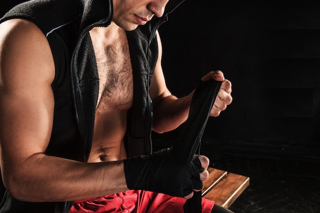 Foto gratuita las manos con vendaje de kickboxing de entrenamiento de hombre musculoso en negro