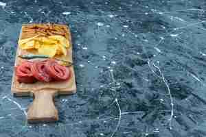 Foto gratuita manteca de cerdo, pescado, patatas fritas y pan rallado sobre una tabla de cortar, sobre el fondo azul.