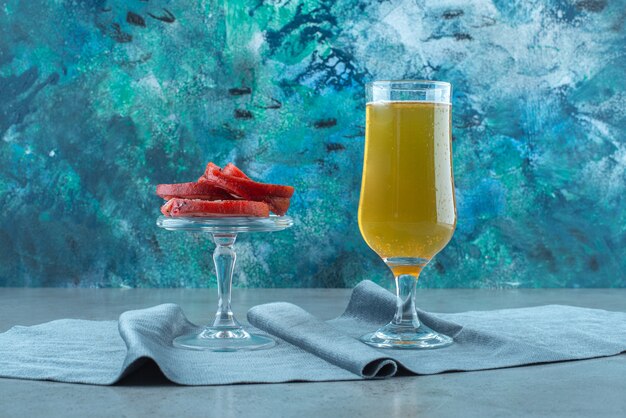 Manteca de cerdo en un recipiente de vidrio y un vaso de cerveza sobre un trozo de tela, sobre la mesa azul.
