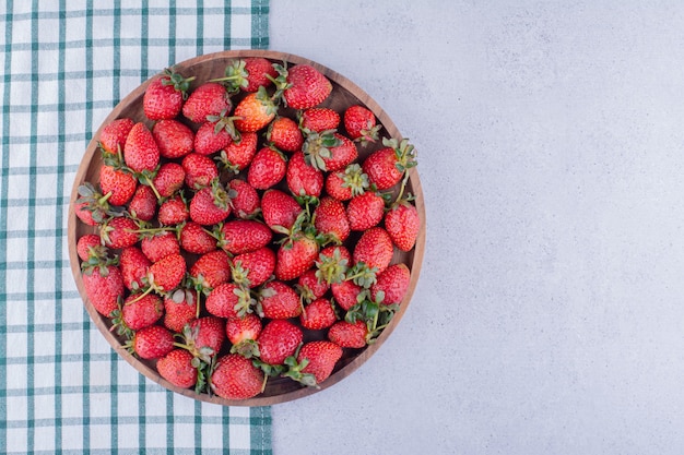 Foto gratuita mantel debajo de un gran cuenco lleno de fresas sobre fondo de mármol. foto de alta calidad