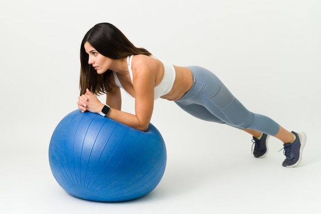 Mantener mi peso ideal con ejercicio. Mujer joven sana y en forma haciendo una tabla en una pelota de estabilidad durante su rutina diaria de ejercicios