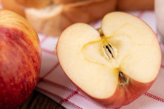 Manzana cortada por la mitad sobre un paño blanco rojo colocado sobre una mesa de madera