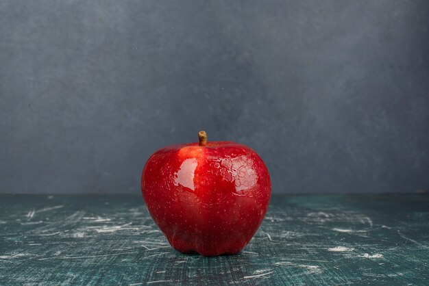 Manzana entera roja sobre fondo azul.