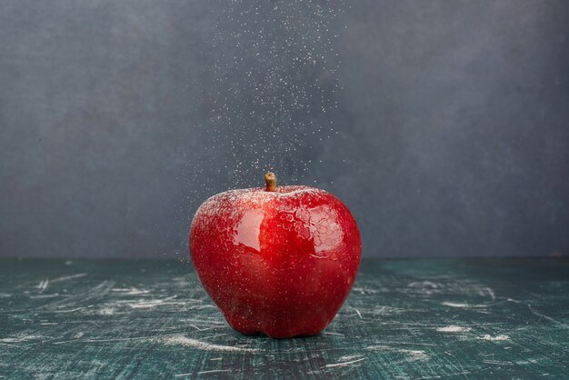 Manzana entera roja sobre mesa azul.