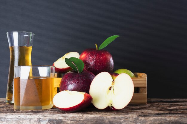 Manzana fresca en caja de madera con jugo de manzana sobre negro, fruta fresca y producto de jugo