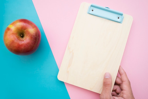 Manzana y mano sujetando portapapeles